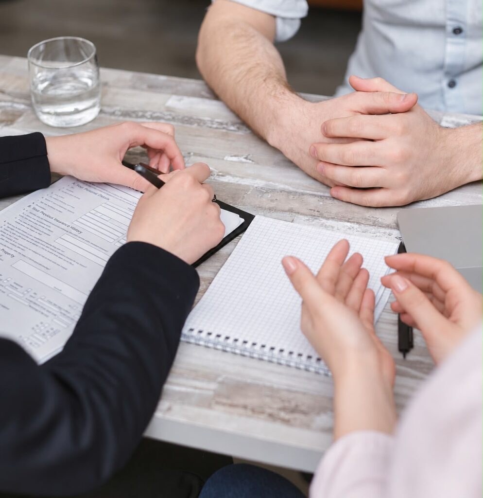 Zwei Personen im Beratungsgespräch an einem Tisch mit Unterlagen